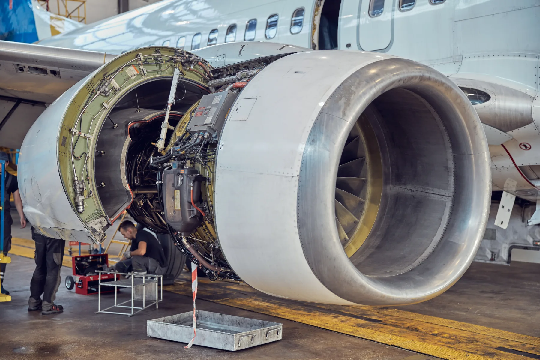 Maintenance work on an open engine nacelle of a passenger aircraft in a hangar.